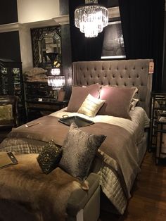 a bedroom with a large bed and chandelier hanging from the ceiling