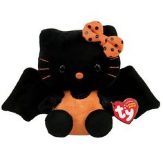 a black and orange stuffed cat with polka dots on it's head sitting next to a red heart