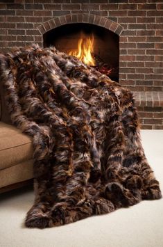 a fireplace with a fire in it and a fur blanket on the floor next to it