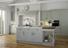 a large kitchen with white cabinets and wooden flooring, along with a clock on the wall