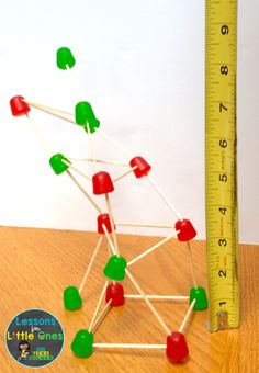 a wooden table topped with lots of green and red pins next to a measuring ruler