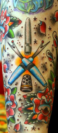 a tattoo on the leg of a person with scissors and flowers around it, in front of