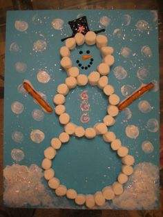 a snowman made out of marshmallows on top of a blue board