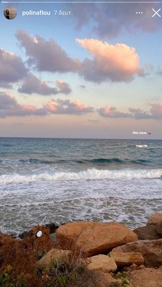 an ocean view with waves crashing on the shore and clouds in the sky above it