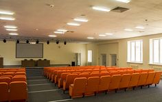 an empty auditorium with rows of orange chairs