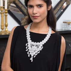 a woman in a black dress wearing a white necklace