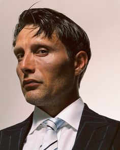 a man in a suit and tie looking off to the side with his head tilted