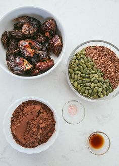 bowls filled with different types of food on top of a white counter next to two glasses