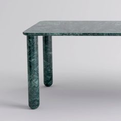 a green marble table sitting on top of a white floor next to a gray wall