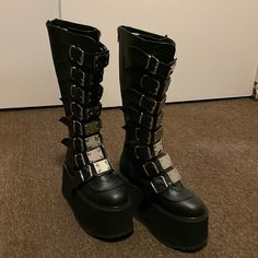 Brand New Demonia Platform Boots Size 7. Never Worn In Original Box. Platform Boots With Round Toe For Concert, Round Toe Platform Boots For Concert, Black Knee-high Platform Moto Boots, High-top Platform Boots With Buckle For Parties, High-top Platform Boots With Buckle Closure For Party, High-top Buckle Platform Boots For Party, Black Closed Toe Platform Boots With Buckle, Black Platform Boots With Buckle Closure, Black Closed Toe Platform Boots With Buckle Closure