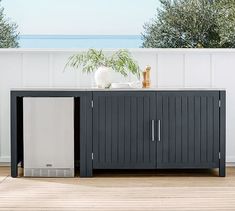 a black and white cabinet sitting on top of a wooden floor next to a plant