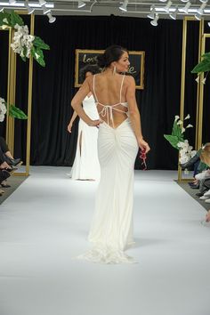 a woman is walking down the runway in a white dress with open back and straps