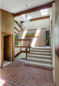 a staircase leading up to the second floor in a home with tile floors and wood paneling