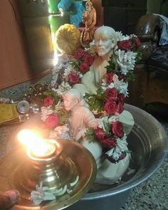 a candle is lit in front of a statue with flowers and other items on the table