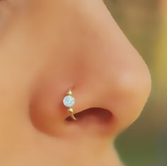 a close up of a person's nose with an opal piercing