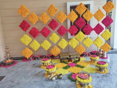 a table topped with lots of flowers next to a wall covered in yellow and pink squares