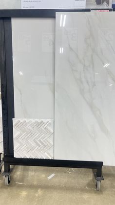 a white marble counter top sitting on wheels in a store display case with black trim