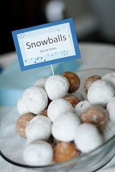 a bowl filled with donuts on top of a table next to a sign that says snowballs