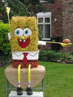 a lawn decoration that looks like a hay bale character holding a broom and wearing a red tie