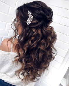 a woman wearing a hair comb with flowers on it's head, in front of a brick wall