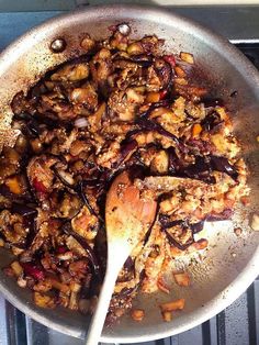 a pan filled with food and a wooden spoon on top of the stove burner