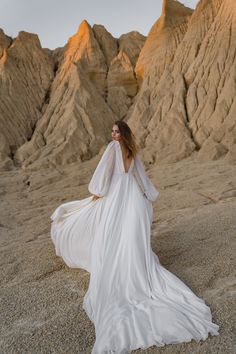 a woman in a white dress is standing on the sand