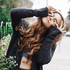 a woman with long hair is posing for the camera and holding her hands up to her face