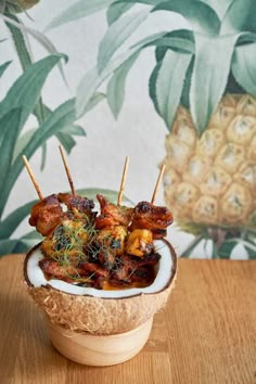 a wooden bowl filled with meat and vegetables on skewered toothpicks next to a pineapple wallpaper