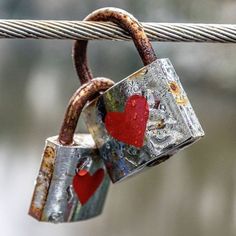 two padlocks attached to a rope with red hearts on them, hanging from it