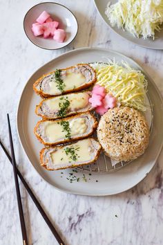 some food is on a white plate with chopsticks next to it and two bowls