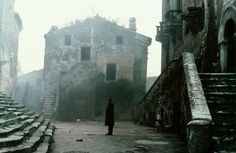 a person standing in an alleyway between two buildings with stone steps leading up to them