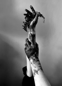 two hands reaching up to each other holding flowers