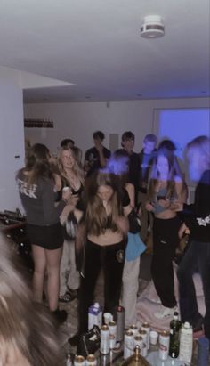 a group of people standing around each other in a room with bottles on the floor