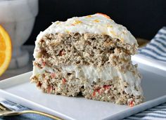 a slice of cake with white frosting and oranges on the side sitting on a plate