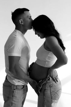 a man and woman kissing each other while standing next to each other in front of a white background