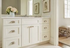 a bathroom with white cabinets and flowers on the counter