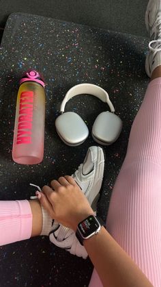 a person wearing headphones and pink leggings sitting next to a water bottle