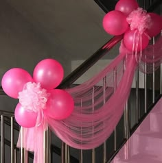 pink balloons and streamers are hanging down the stairs