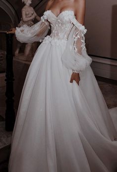 a woman in a white wedding dress standing on stairs with her arms behind her back