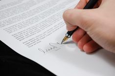 a hand holding a pen writing on top of a piece of paper with the words land in kealaa