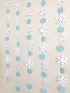 paper snowflakes are hanging on the wall with blue circles and dots around them