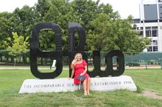 a woman sitting in front of a big sign