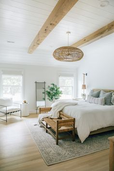 a bedroom with white walls, wood beams and a large bed in the middle of the room