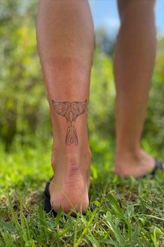 a person with a tattoo on their foot walking in the grass and looking at the ground