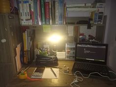 a laptop computer sitting on top of a wooden desk next to a book shelf filled with books