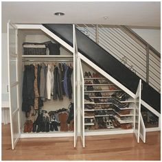 an open closet under stairs with shoes and bags