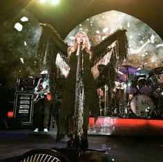 a woman standing on top of a stage holding her arms out