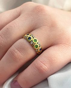 a close up of a person's hand with a gold ring on it and three different colored stones