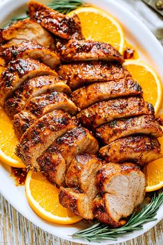 sliced pork and oranges on a white plate