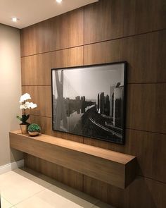 a tv mounted to the side of a wooden wall next to a vase with flowers